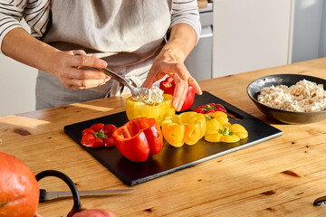 Woman food blogger preparing stuffed colorful bell peppers with ricotta cheese for Halloween party. Peppers carved like Jack-o-lantern scary face. Halloween food idea.