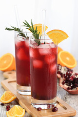 Pomegranate orange holiday punch with ice and rosemary. This is a sweet, tart and refreshing cocktail perfect for celebrating any party.