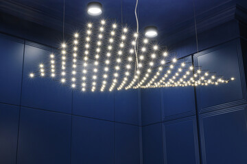 A chandelier of many led light bulbs hanging on the ceiling in the form of a wave. Led light...