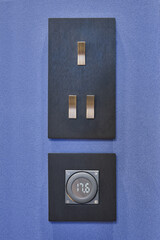 Power switch on a  blue wall and temperature heating system controller. Digital temperature controller and brass light buttons