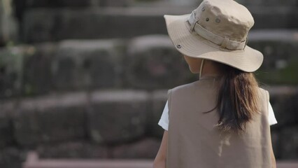 A little girl is using binoculars and exploring a rock castle.