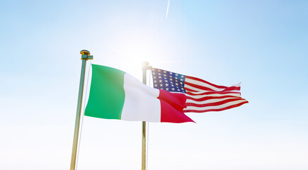 Italy and United states flags waving against a blue sky background. 