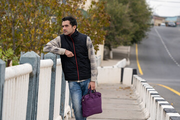 Fototapeta premium Armenian man, different emotional face actions, in the outdoor, the cold temperature, with the jacket, the man with the suitcase looking side
