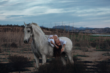 Portrait of a white horse and sexy woman. Beautiful glamour woman with a horse. Portrait of a beauty undressed woman with horse.