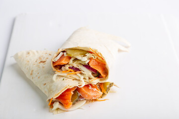 Pita roll with salmon and vegetables filling. Shawarma in pita bread stuffed with vegetables and fish
