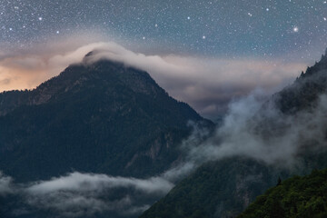 Beautiful fantasy night landscape, mountains in in the clouds at the night.
