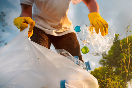 Volunteer teenage boys are holding garbage bags and Collecting plastic bottle waste at public parks for recycling, Reuse, and waste management concepts.
