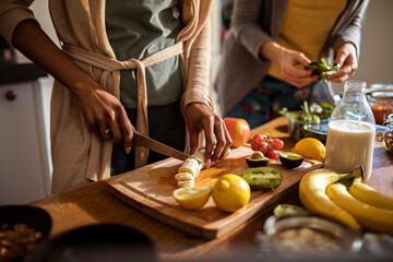 Close-up of a woman cutting up bananas for healthy smoothie in the kitchen