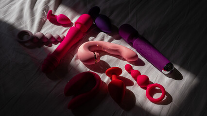 A set of sex toys on a white sheet. Personal collection of dildos. - obrazy, fototapety, plakaty