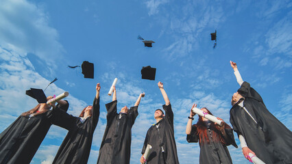 Joyful graduates stand in a row and toss their caps up in the air.
