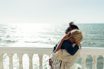 .The mother holds her son in her arms against the backdrop of the sea.