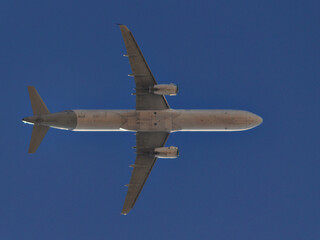low view of a jet plane flying at low altitude under a blue sky.