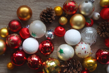 Pine cones and red, golden and white Christmas ornaments on wooden background. Top view.