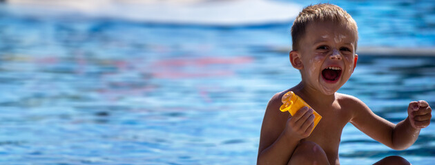 child by the pool applying sunscreen.