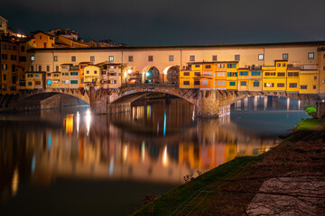 Obraz premium The Ponte Vecchio in Florence, Italy, at night with the reflection of the bridge and lights in the river