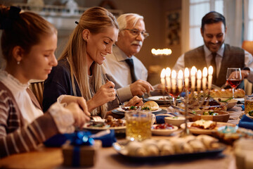 Happy Jewish woman enjoys in meal with her family on Hanukkah. - obrazy, fototapety, plakaty