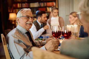 Happy Jewish senior man toasting with his wife during family gather on Hanukkah.