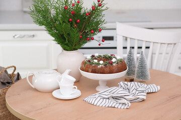 Christmas home interior in white kitchen-Christmas chocolate bundt cake with fresh berries and rosemary. Winter baking at Christmas. Ceramic vase with spruces brunches..