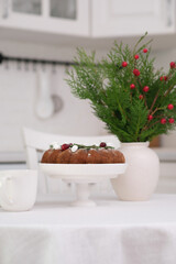 Christmas home interior in white kitchen-Christmas chocolate bundt cake with fresh berries and rosemary. Winter baking at Christmas. Ceramic vase with spruces brunches..