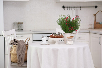 Christmas home interior in white kitchen-Christmas chocolate bundt cake with fresh berries and rosemary. Winter baking at Christmas. Ceramic vase with spruces brunches..