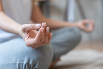 Closeup nails female hands serene mature woman athlete yogi meditating in lotus position with eyes...