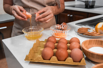 Hands cracking eggs to make a dessert in a home kitchen