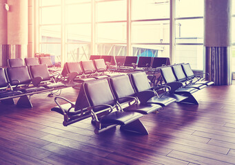 Empty seats in an airport departure hall at sunset, color toned picture, selective focus.