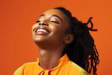 Foto op Canvas A cheerful African woman wearing makeup, her eyes closed as she smiles with satisfaction. orange studio background © Creative Clicks