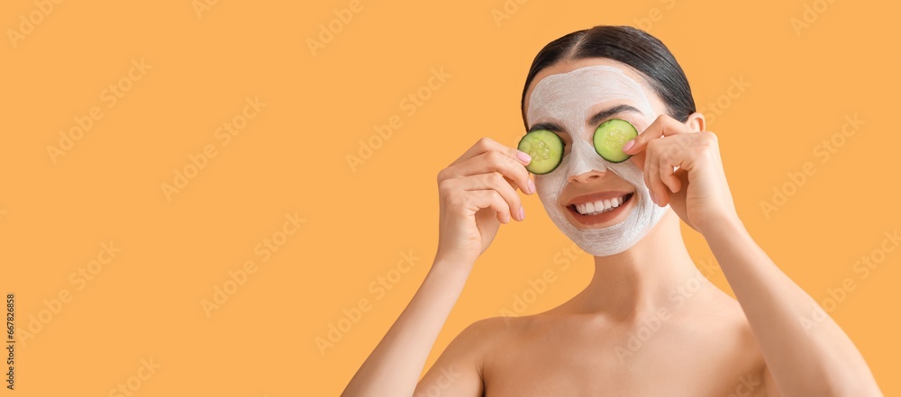 Wall mural beautiful young woman with cucumber slices and facial mask on orange background with space for text.