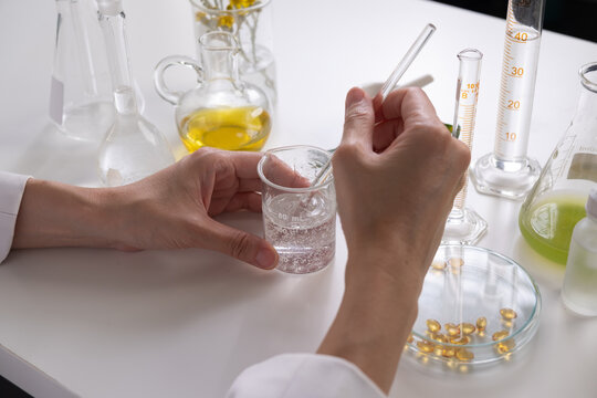 Scientists produce skincare gel or serum in the laboratory from natural ingredients, herbal oils, and vitamins. Health, cosmetic, beauty, and wellness concept.