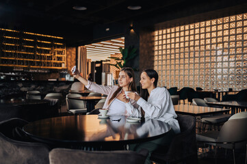 Happy girls posing in a coffee shop while taking selfies.