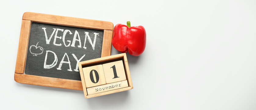 Calendar with date NOVEMBER 1, bell pepper and chalkboard with text VEGAN DAY on white background with space for text