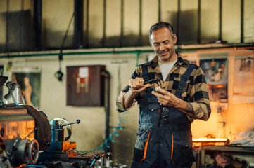 Fototapeta na wymiar A metal processing worker examining a metal ring next to a machine.