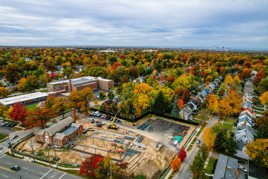 Aerial view of a huge crane moving steel for Noble library's construction, surrounded by colorful fall trees and suburbs