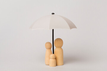 Wooden family figures with umbrella on color background