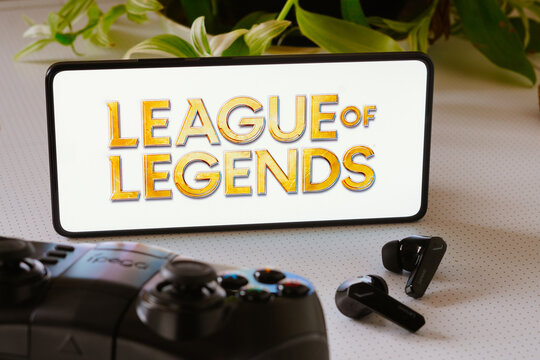 October 25, 2023, Brazil. In this photo illustration, the League of Legends game logo is displayed on a smartphone screen, next to a gamepad and headphones.