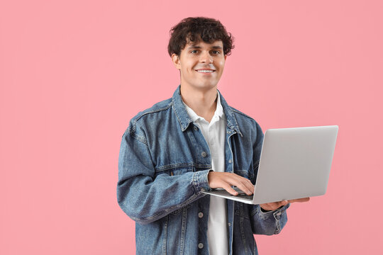 Male programmer working with laptop on pink background