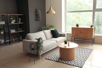 Interior of modern living room with comfortable grey sofa and wooden coffee table