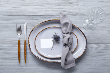 Stylish modern table setting with card on grey wooden background