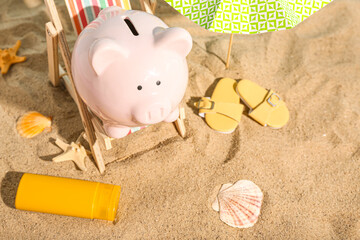 Creative composition with piggy bank, beach accessories and sunscreen cream on sand. Concept of...