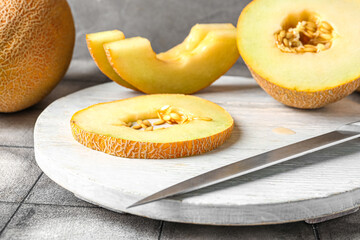Board with pieces of sweet melon on grey tile table