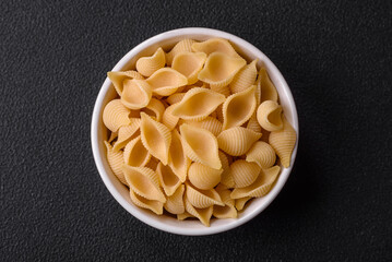 Raw Italian pasta conchiglie from durum wheat with vegetables, salt and spices