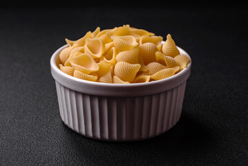 Raw Italian pasta conchiglie from durum wheat with vegetables, salt and spices