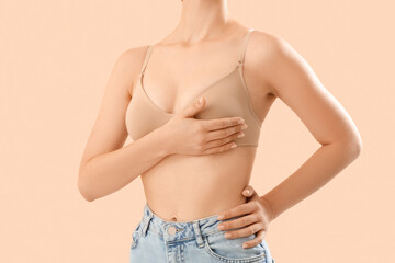 Young woman in bra on beige background