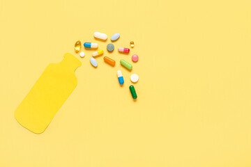 Paper bottle and different pills on yellow background