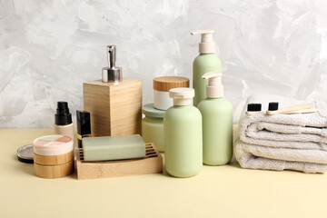Set of different cosmetic products, towels and toothbrushes on color table