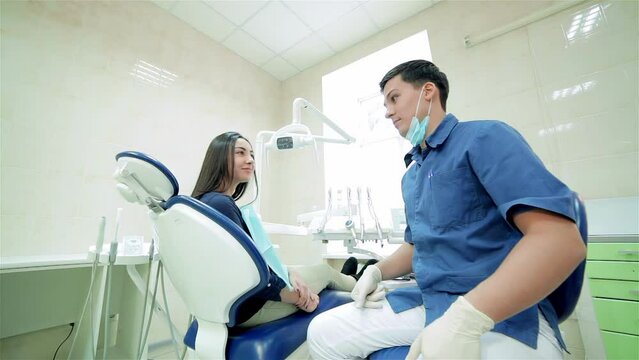 The dentist speaks to the patient, then they rotate together and show a thumbs up to the camera
