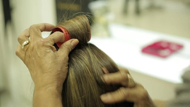 close up of woman curling hair with curlers of a blonde woman in beauty salon
