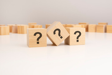 row of three wooden blocks question marks on viewed angle on a white background