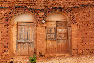 Casa de adobe con ventanas y puertas de madera antiguas.